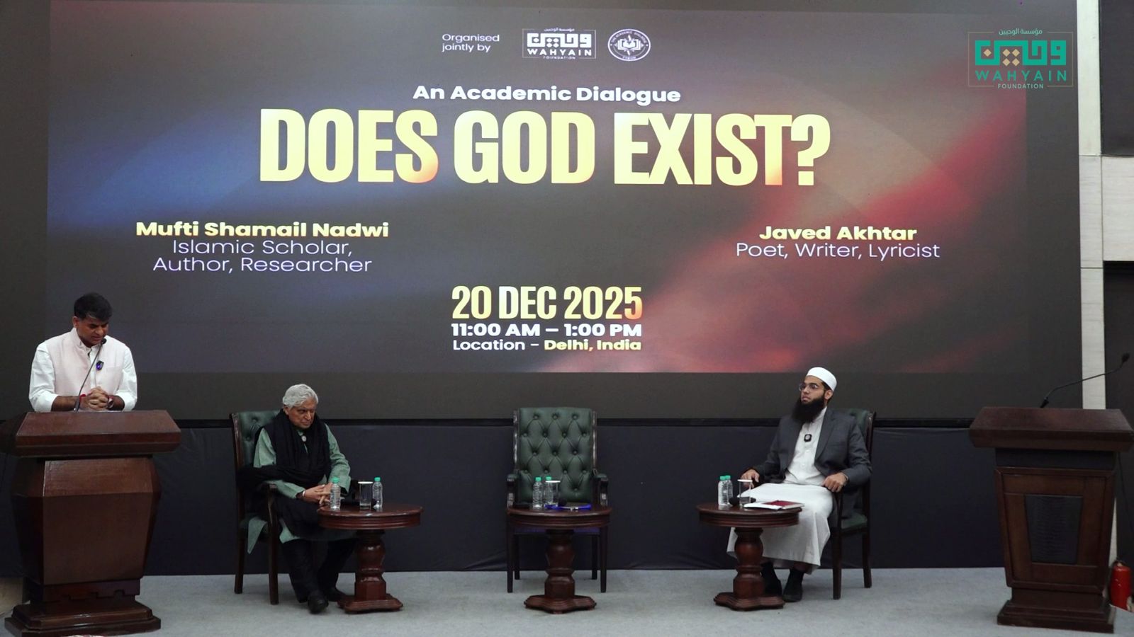 Mufti Shamail Nadwi and Javed Akhtar on stage under the screen reading Does God Exist?